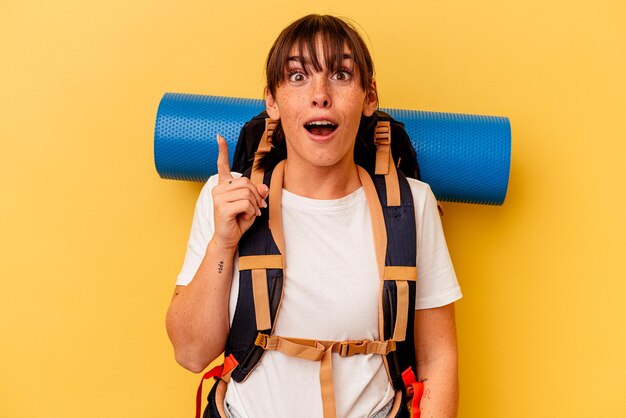 Mulher jovem alpinista argentina isolada em fundo amarelo, tendo uma ideia, conceito de inspiração.