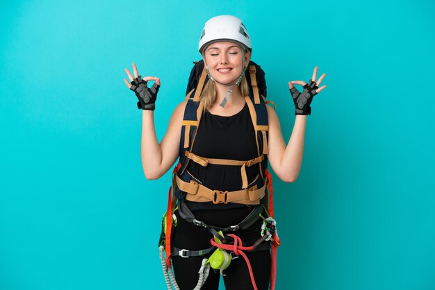 Mulher jovem alpinista caucasiana isolada em fundo azul em pose zen