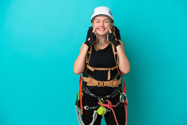 Mulher jovem alpinista caucasiana isolada em fundo azul sorrindo com uma expressão feliz e agradável