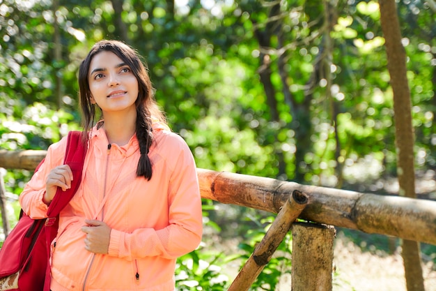 Mulher jovem alpinista com mochila vermelha olhando para a natureza