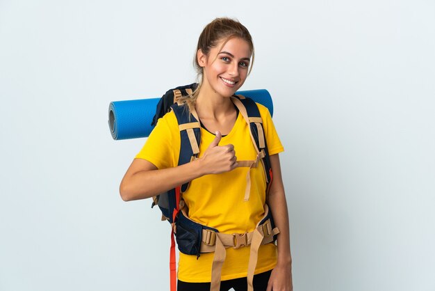 Mulher jovem alpinista com uma grande mochila posando isolada contra a parede em branco