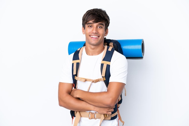 Mulher jovem alpinista com uma mochila grande sobre fundo branco isolado com os braços cruzados e olhando para a frente