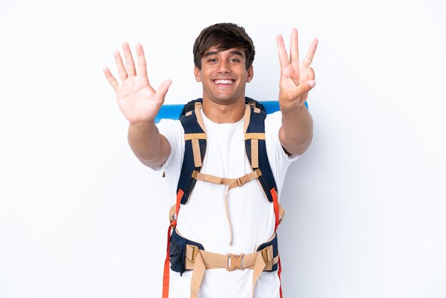 Foto mulher jovem alpinista com uma mochila grande sobre fundo branco isolado, contando oito com os dedos