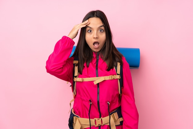 Mulher jovem alpinista com uma mochila grande sobre parede rosa isolada acaba de perceber algo e tem a intenção de a solução