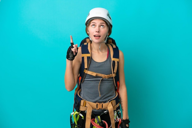 Mulher jovem alpinista inglesa isolada em fundo azul apontando para cima e surpresa