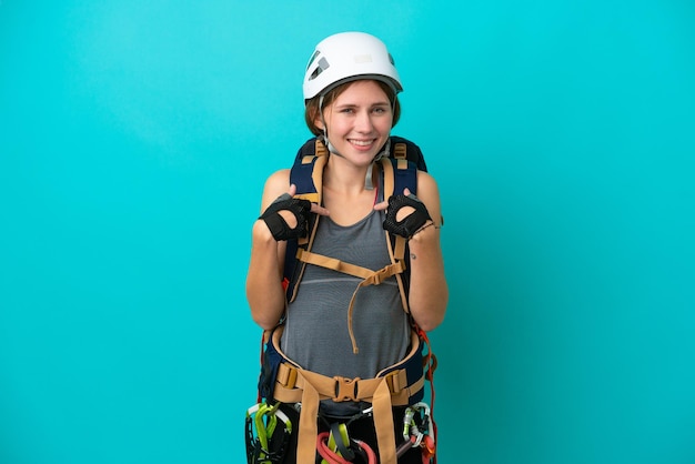 Mulher jovem alpinista inglesa isolada em fundo azul com expressão facial de surpresa