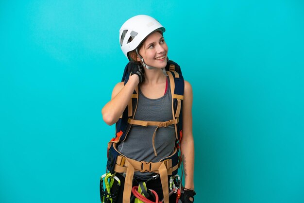 Mulher jovem alpinista inglesa isolada em fundo azul, pensando em uma ideia