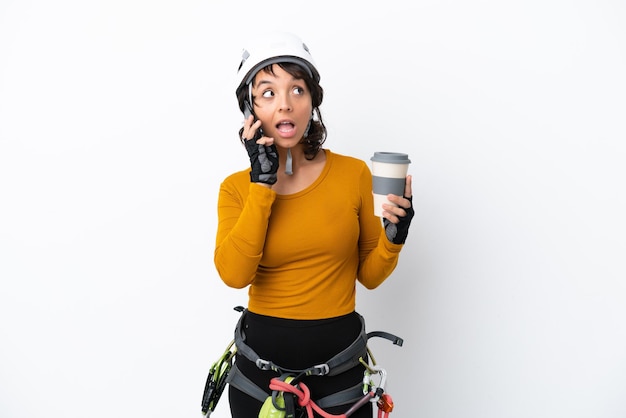 Mulher jovem alpinista isolada no fundo branco segurando um café para levar e um celular