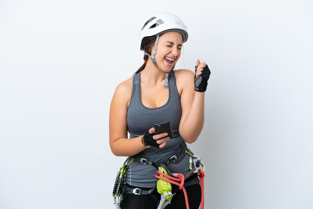 Mulher jovem alpinista ucraniana isolada em fundo branco com telefone em posição de vitória