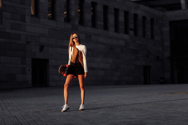 Mulher jovem anda de longboard pela cidade. Foto de alta qualidade