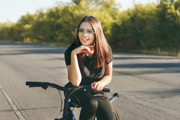 Mulher jovem andando de bicicleta na estrada