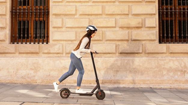 Foto mulher jovem andando em uma scooter elétrica na cidade