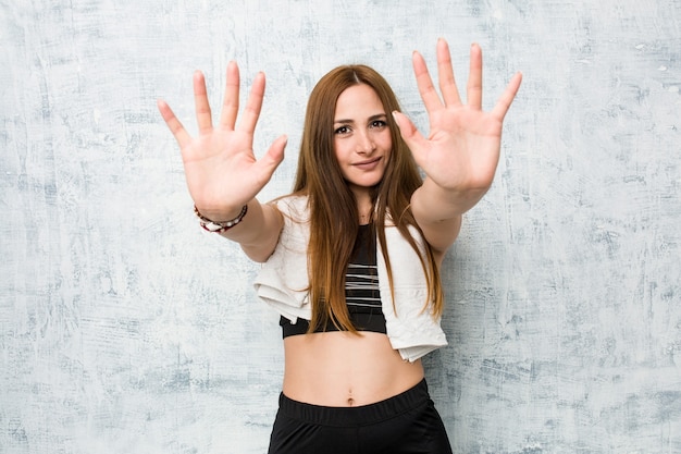 Mulher jovem aptidão mostrando o número dez com as mãos.
