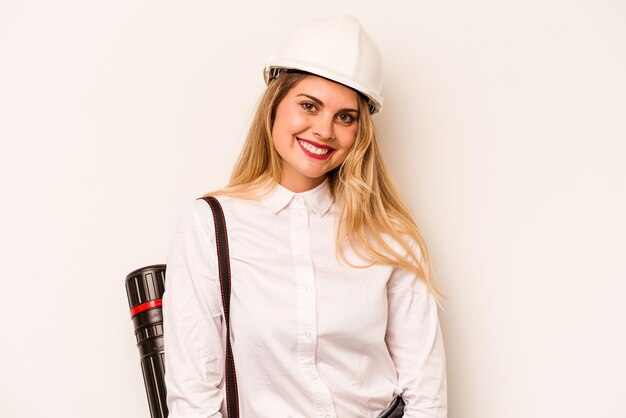 Mulher jovem arquiteta com capacete e segurando plantas isoladas em fundo branco feliz sorrindo e alegre