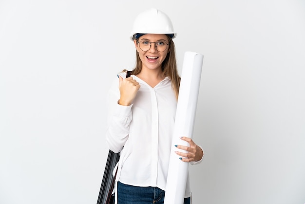 Mulher jovem arquiteta lituana com capacete e segurando plantas isoladas no fundo branco apontando para o lado para apresentar um produto