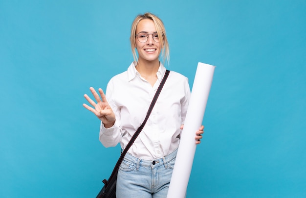 Mulher jovem arquiteta sorrindo e parecendo amigável, mostrando o número quatro ou o quarto com a mão para a frente, em contagem regressiva