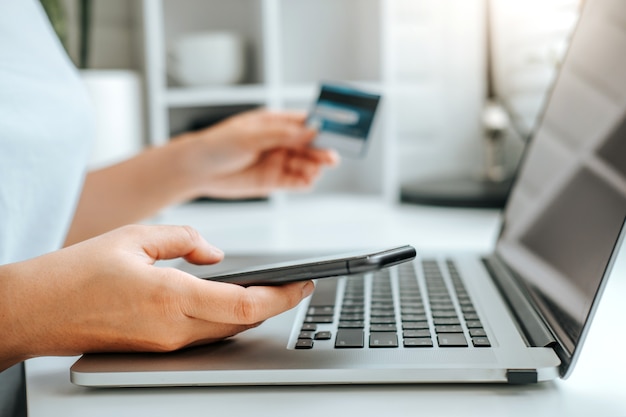 Mulher jovem asiática descansando e navegando na internet com o laptop segurando o conceito de compras online de cartão de crédito