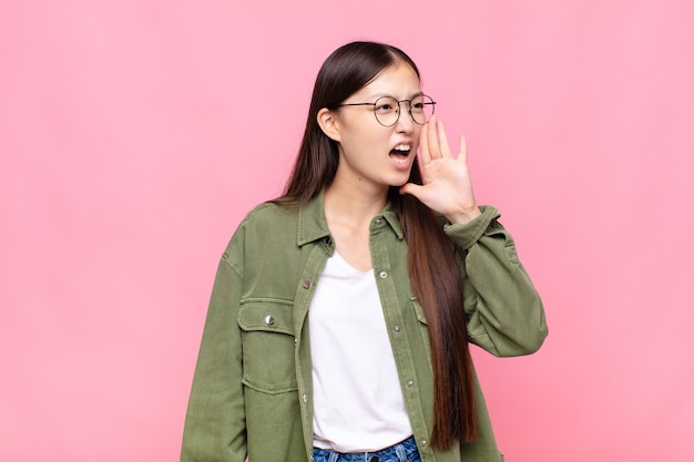 Mulher jovem asiática gritando alto e com raiva isolada