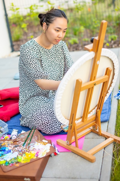 Mulher jovem asiática pintando foto no terraço de casa