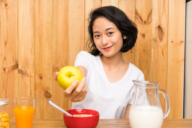 Mulher jovem asiática tomando café da manhã e com uma maçã