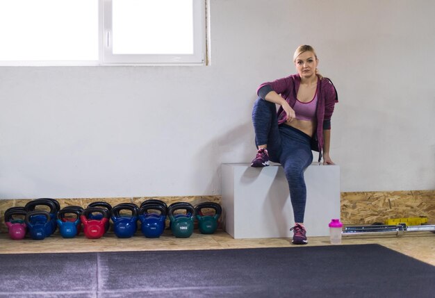 mulher jovem atleta sentado e relaxando após o exercício no ginásio de fitness cross