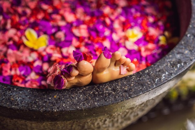 Mulher jovem atraente no banho com pétalas de flores tropicais e óleos aromáticos Tratamentos de spa para rejuvenescimento da pele Mulher sedutora no salão de spa Garota relaxando na banheira com pétalas de flores Luxo