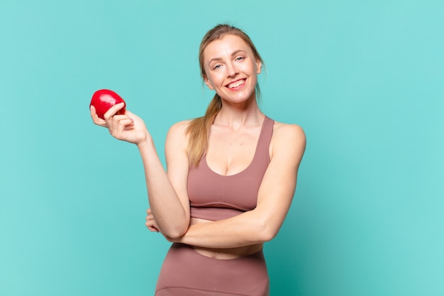 Mulher jovem bonita com expressão de felicidade e segurando uma maçã