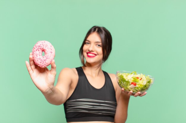 Mulher jovem bonita com expressão feliz e segurando uma salada