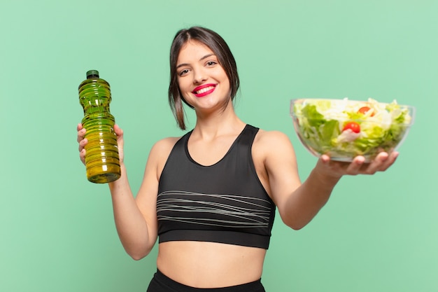 Mulher jovem bonita com expressão feliz e segurando uma salada