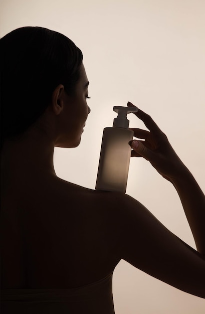 Mulher jovem bonita com frasco de cosméticos e testando cosméticos em sua pele