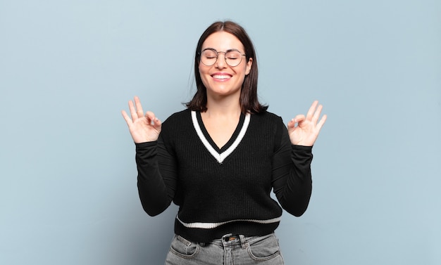 Mulher jovem, bonita e casual, parecendo concentrada e meditando, sentindo-se satisfeita e relaxada, pensando ou fazendo uma escolha