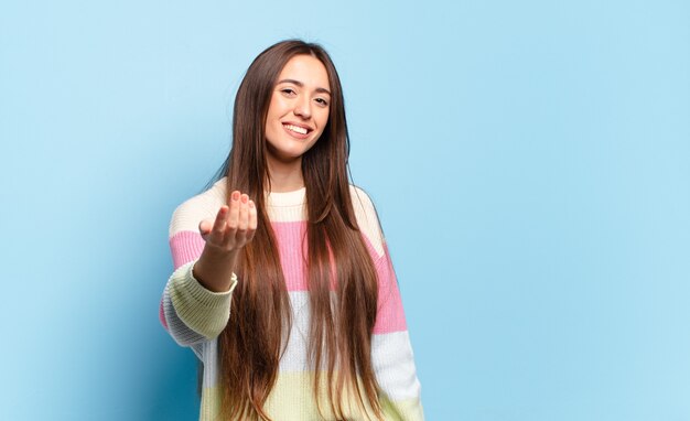 Mulher jovem, bonita e casual, sentindo-se feliz, bem-sucedida e confiante, enfrentando um desafio e dizendo para você! ou dando boas-vindas a você