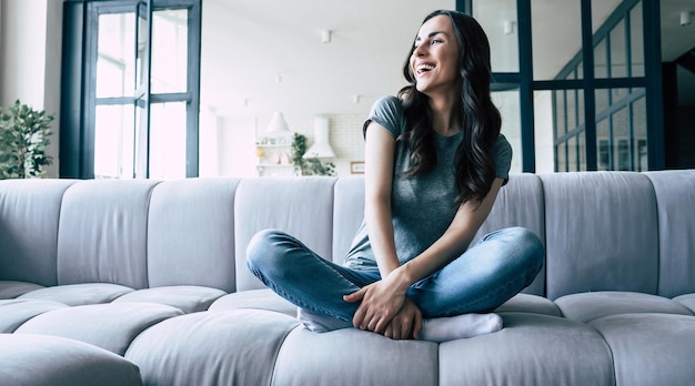 Foto mulher jovem bonita feliz relaxando no sofá em casa e sorrindo