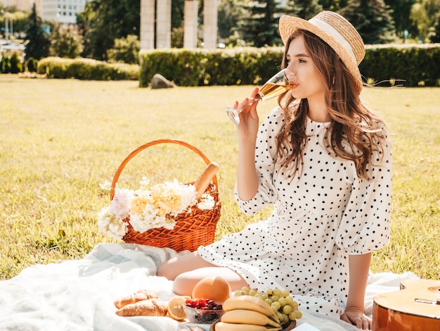 Mulher jovem bonita hippie com vestido de verão na moda e chapéu. Mulher despreocupada fazendo piquenique do lado de fora.