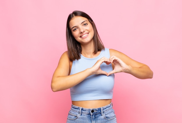 Mulher jovem bonita sorrindo e se sentindo feliz, fofa, romântica e apaixonada isolada