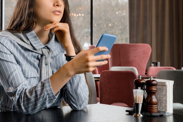 Foto mulher jovem bonita triste com smartphone à espera do namorado no restaurante