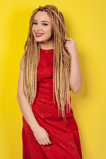 Mulher jovem bonita vestida com um vestido vermelho, tocando tranças africanas