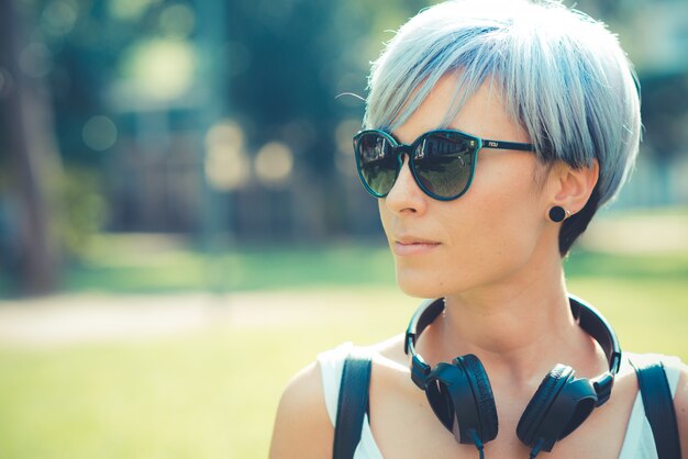 Foto mulher jovem bonito cabelo curto azul hipster com fones de ouvido música