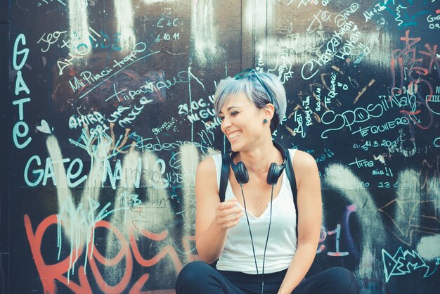 mulher jovem bonito cabelo curto azul hipster com fones de ouvido música