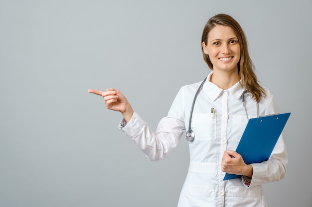 Mulher jovem bonito médico apresentando e apontando