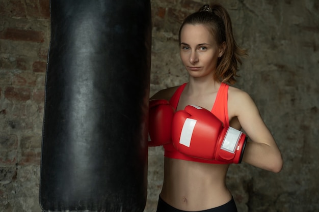 Mulher jovem boxeadora atlética na academia perto da pera perfurando