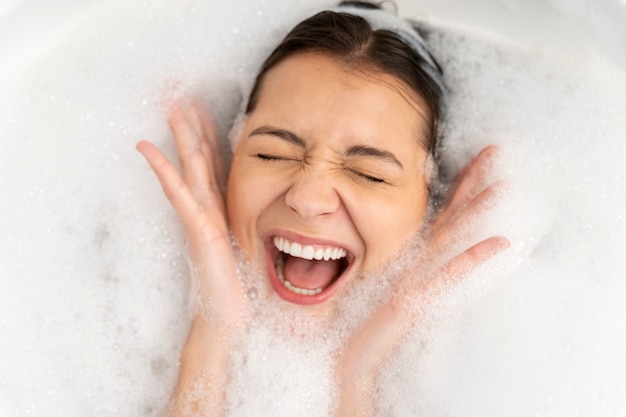 Mulher jovem brincando com a espuma enquanto toma banho