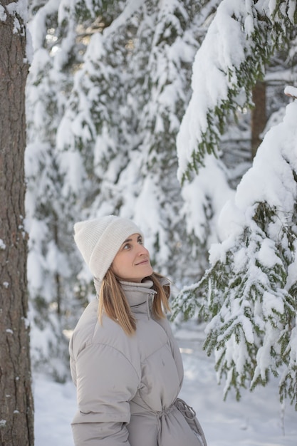 Mulher jovem caminhando em uma floresta de neve de inverno