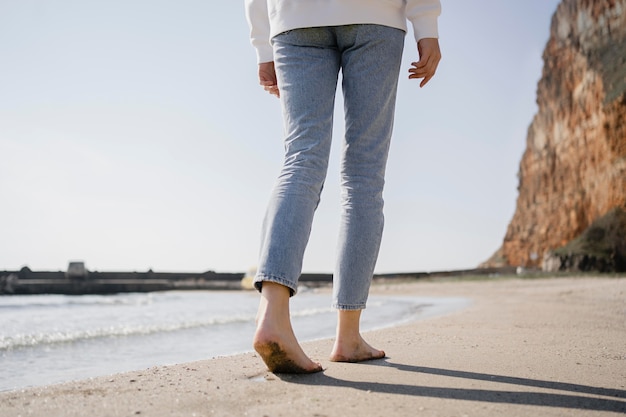 Foto mulher jovem caminhando na areia da praia