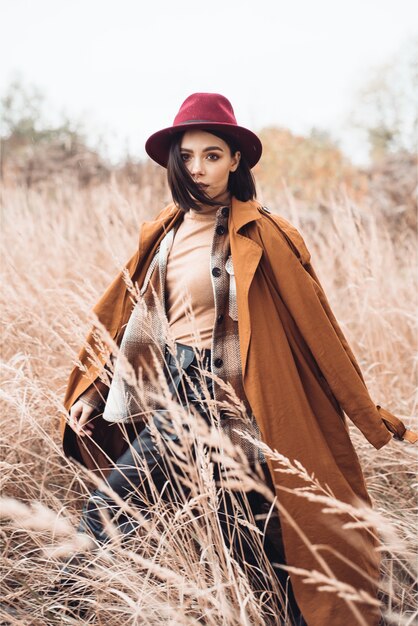 Mulher jovem caminhando pela grama seca no outono