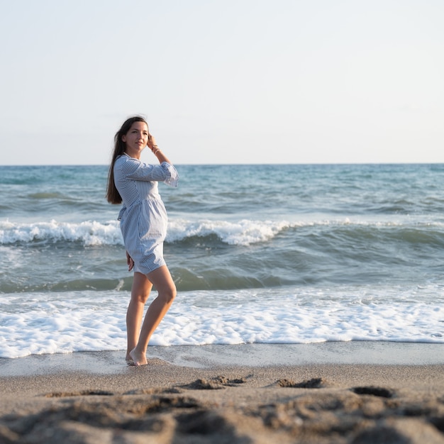 Mulher jovem caminhando perto do mar.