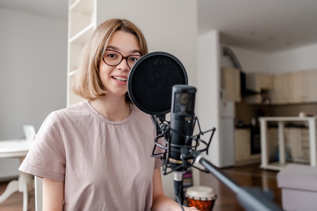 Mulher jovem cantando com microfone e sorrindo em casa