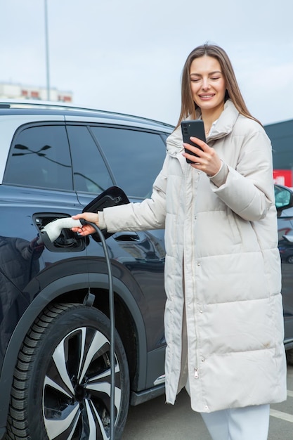 Mulher jovem carregando seu carro elétrico em uma estação de carregamento na cidade Conceito de combustível ecológico