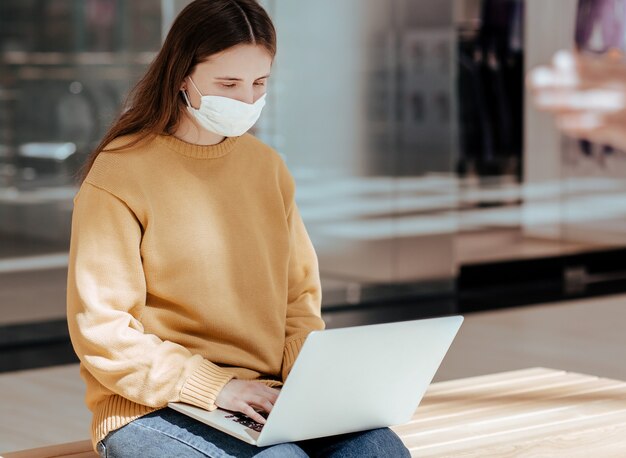 Mulher jovem casual com um laptop em uma rua da cidade.