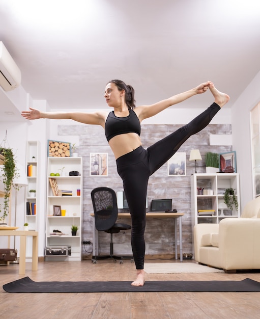 Mulher jovem caucasiana, fazendo uma bela pose de ioga na sala de estar.